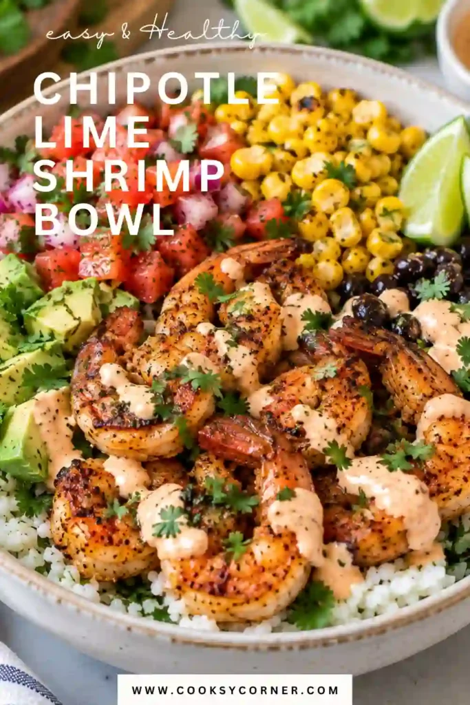 Healthy shrimp bowl featuring chipotle lime shrimp, fluffy rice, fresh spinach, avocado, cucumber, tomatoes, and sliced red onion. Lime wedges and cilantro add a fresh finishing touch.