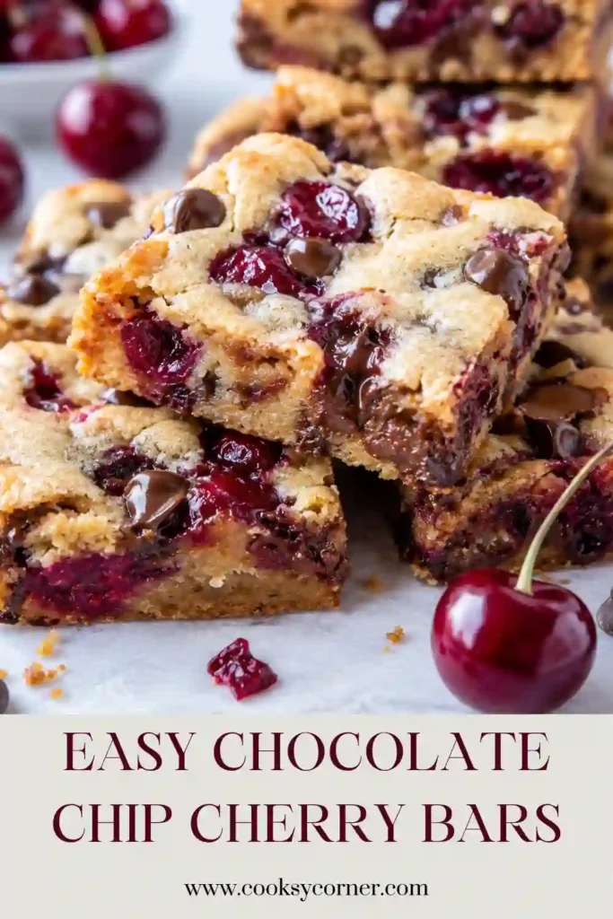 Chocolate Chip Cherry Bars stacked on a serving plate with fresh cherries nearby. The soft blondie bars are filled with juicy fruit and pockets of melted chocolate chips.
