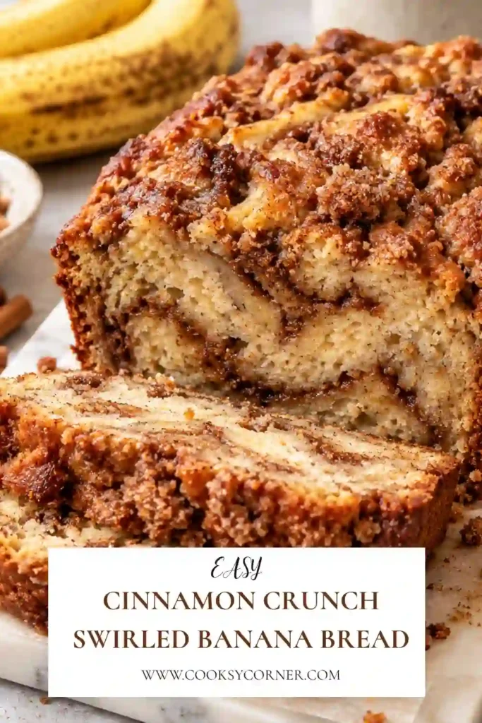 Cinnamon Crunch Swirled Banana Bread sliced on a wooden board with a golden brown cinnamon topping. The moist banana bread reveals a dark cinnamon sugar swirl through the center.