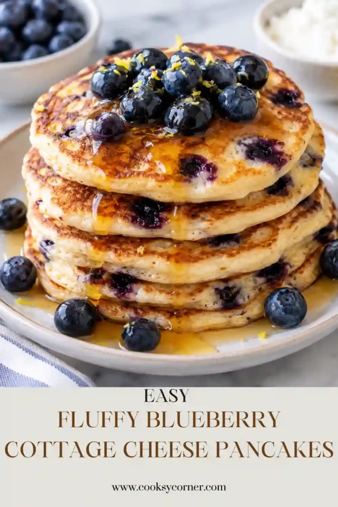 Fluffy blueberry cottage cheese pancakes stacked on a breakfast plate with fresh blueberries and maple syrup. The pancakes have golden edges and thick, tender centers