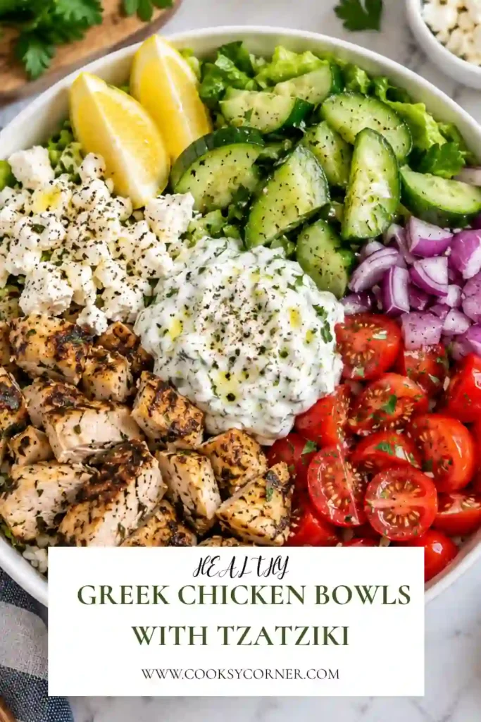 Greek chicken and rice bowl featuring juicy oregano chicken, crisp vegetables, crumbled feta, and creamy tzatziki. A fresh Mediterranean chicken bowl served with cucumber and tomatoes.