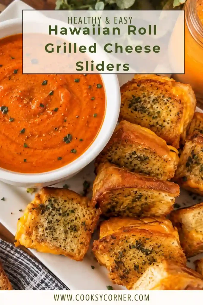 Mini grilled cheese sliders served beside a bowl of tomato soup. The golden Hawaiian-style rolls are filled with melted cheddar and ready for dipping.