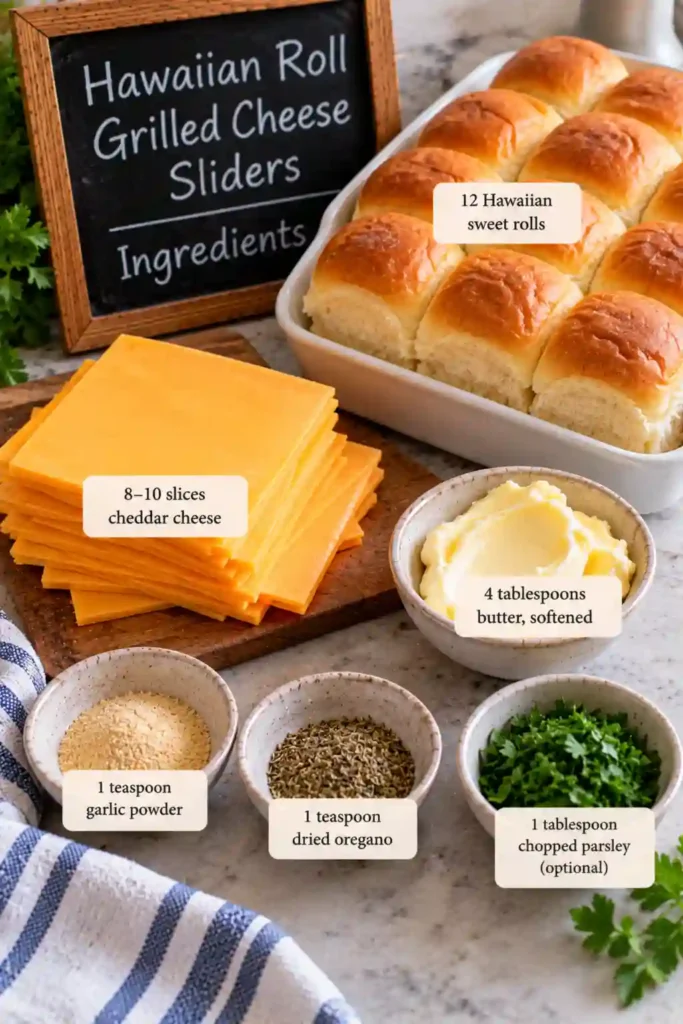 Assembled Hawaiian roll cheese sliders on a parchment-lined baking sheet before baking. The rolls are layered with cheddar and spread with garlic-herb butter