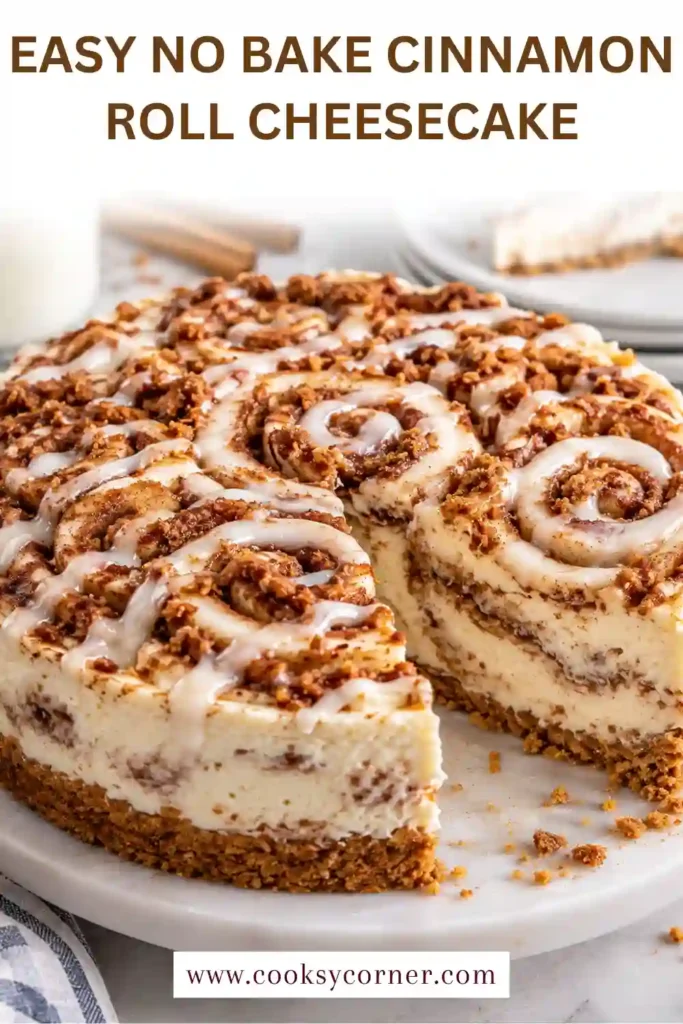 A sliced No Bake Cinnamon Roll Cheesecake showing creamy layers and ribbons of cinnamon caramel filling. The dessert is finished with whipped cream and cinnamon roll cookies.