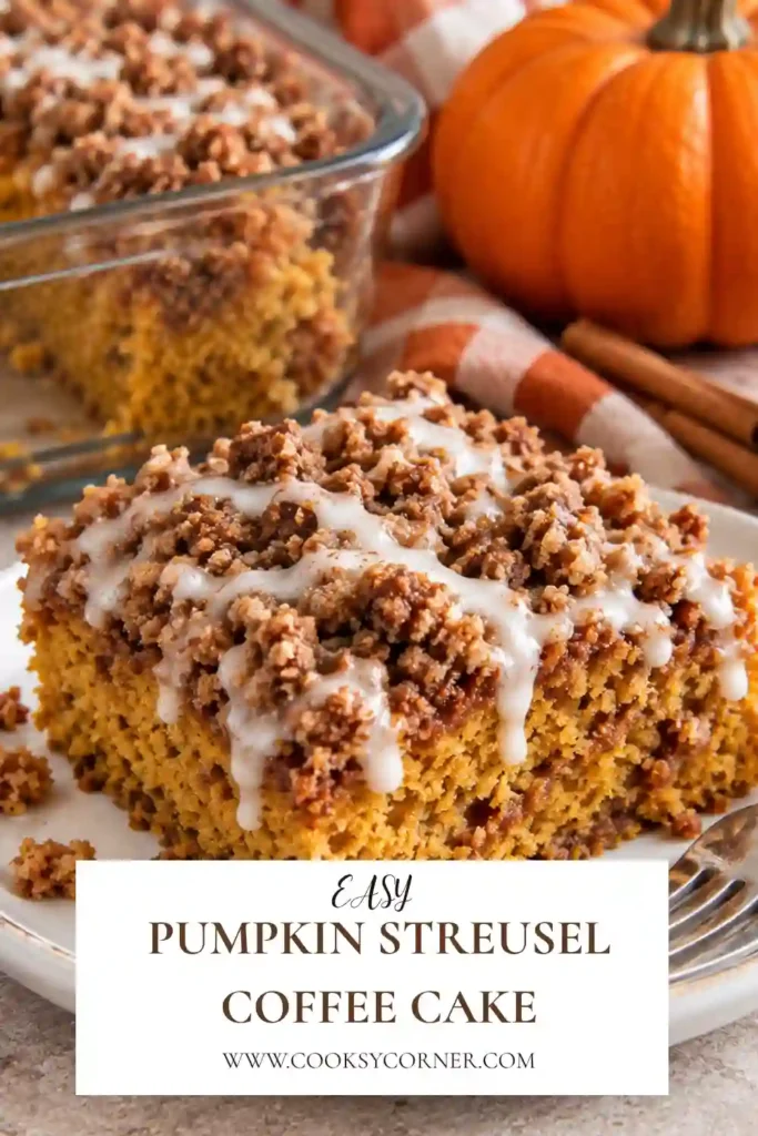 A freshly baked pumpkin streusel coffee cake in a rectangular baking pan with a golden brown sugar crumb topping and chopped pecans. The moist pumpkin cake has a warm, homemade appearance.
