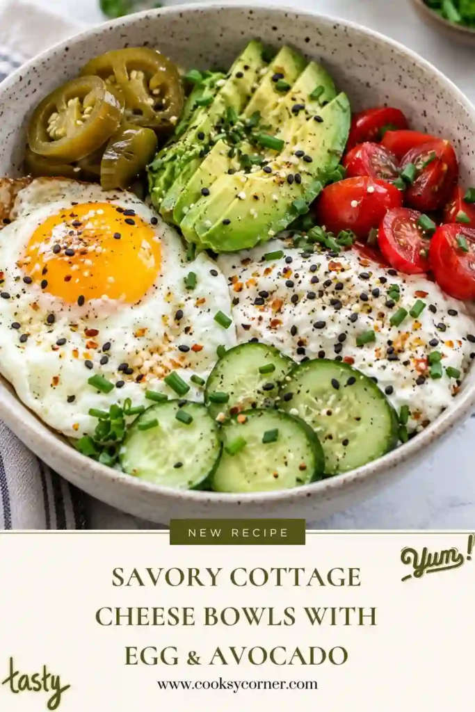 High protein breakfast bowl featuring cottage cheese and a fried egg with a soft yolk, avocado, cucumber, tomatoes, and jalapeño slices. Fresh chives and savory everything seasoning finish the bowl.
