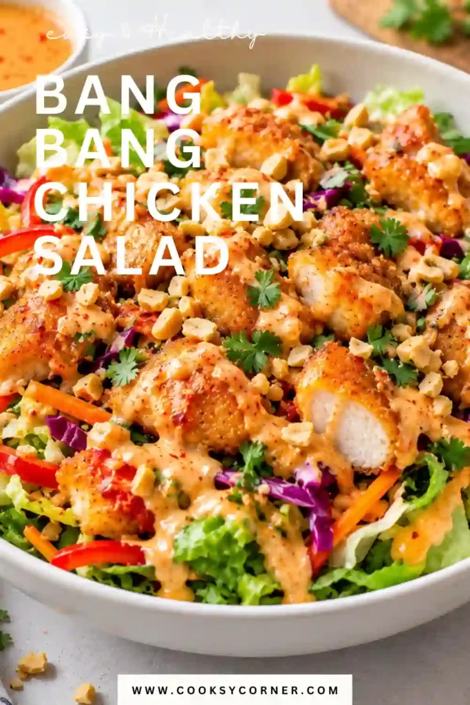 Bang Bang Chicken Salad with shredded chicken, carrots, red bell pepper, scallions, and cilantro coated in creamy spicy dressing. Sesame seeds and fresh herbs add color and texture to the finished salad.