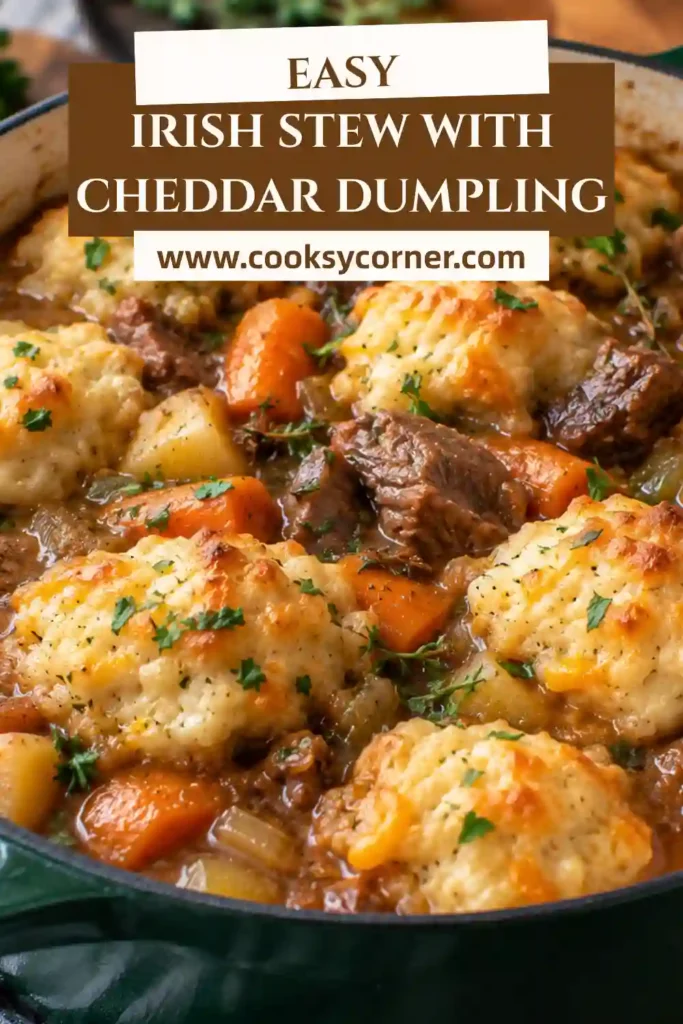 Irish Stew with Cheddar Dumplings served in a rustic cast-iron skillet with tender beef, potatoes, carrots, mushrooms, and golden cheese dumplings. Fresh parsley adds a colorful finish.